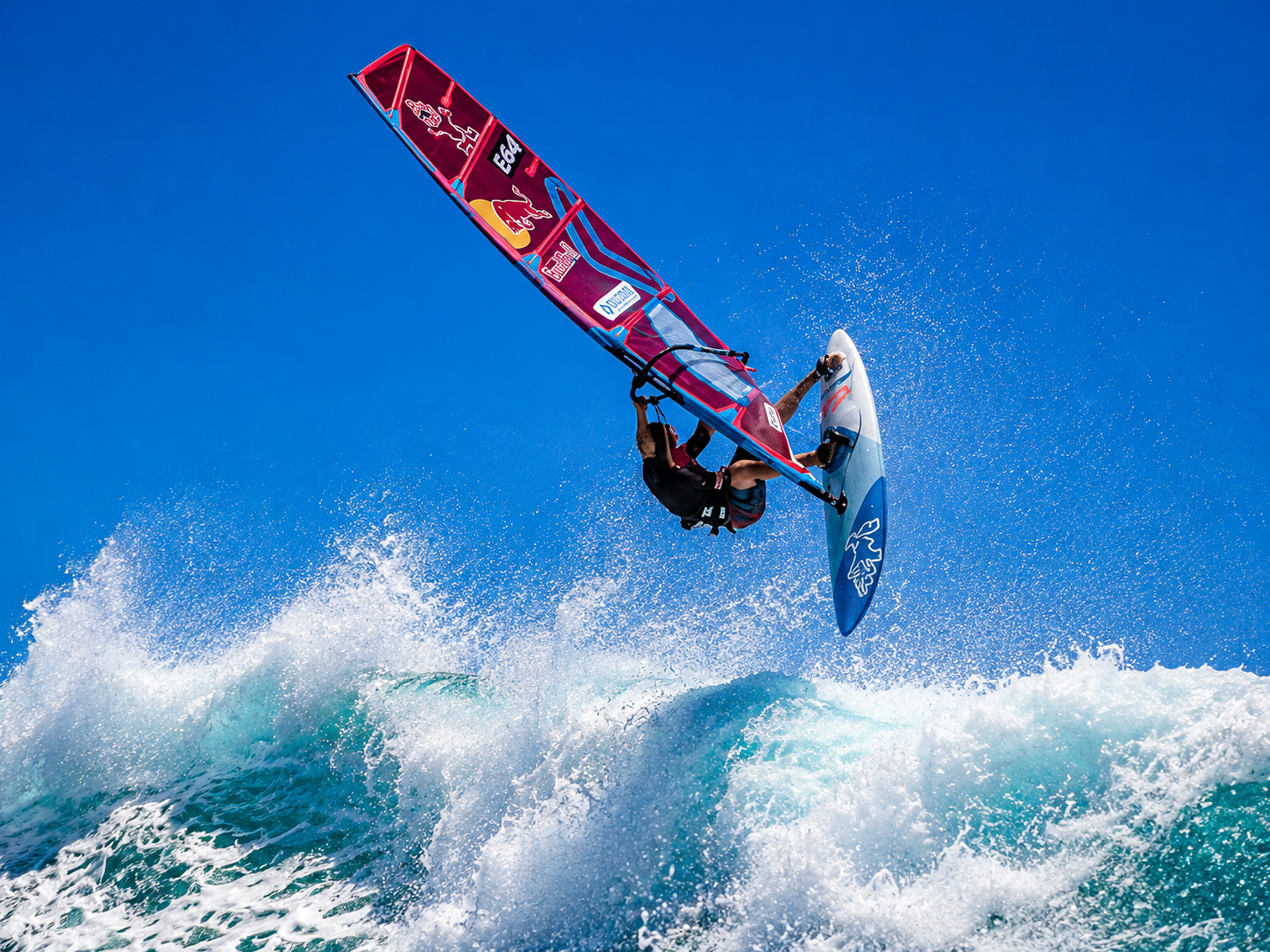 Advanced windsurfer launching high above a breaking wave in strong Red Sea wind