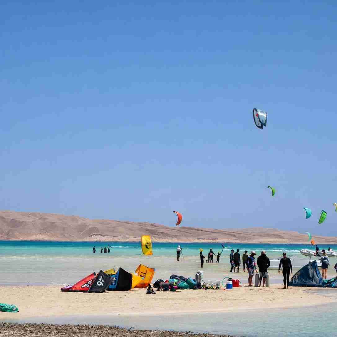 Kitesurfers riding a shallow turquoise lagoon backed by desert