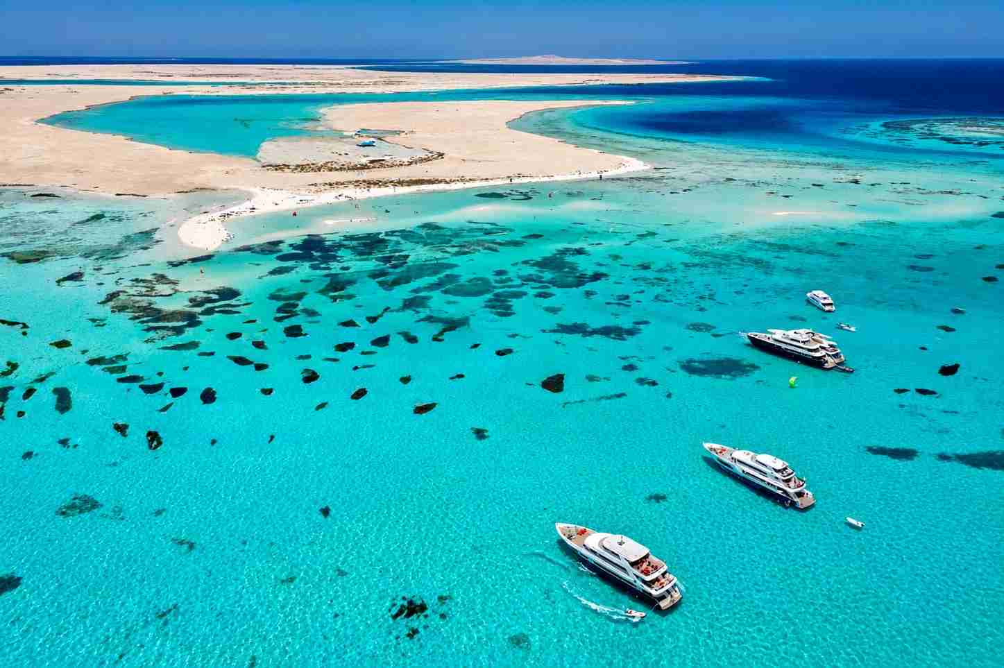 Aerial view of turquoise lagoons, sandy islands and liveaboard boats in the Red Sea
