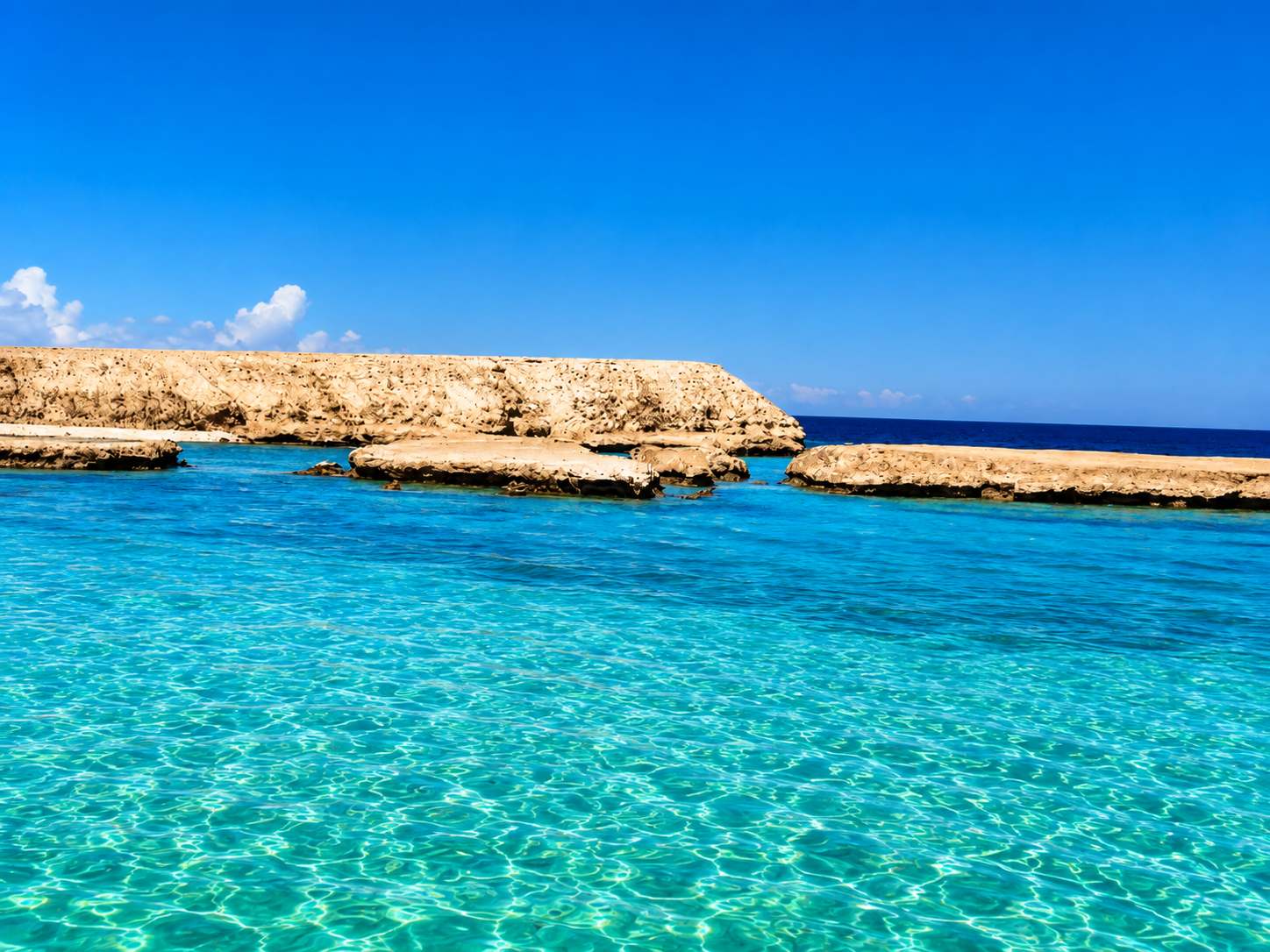 Clear turquoise water over the coral reef formations of Abu Ramada in the Red Sea