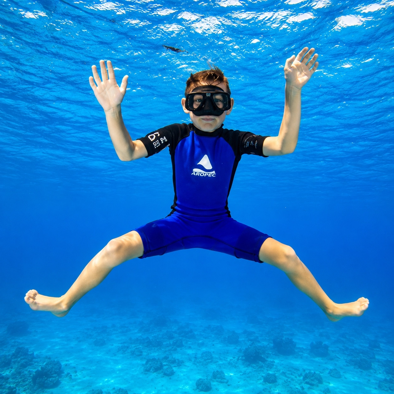 Child floating underwater on scuba in clear shallow water