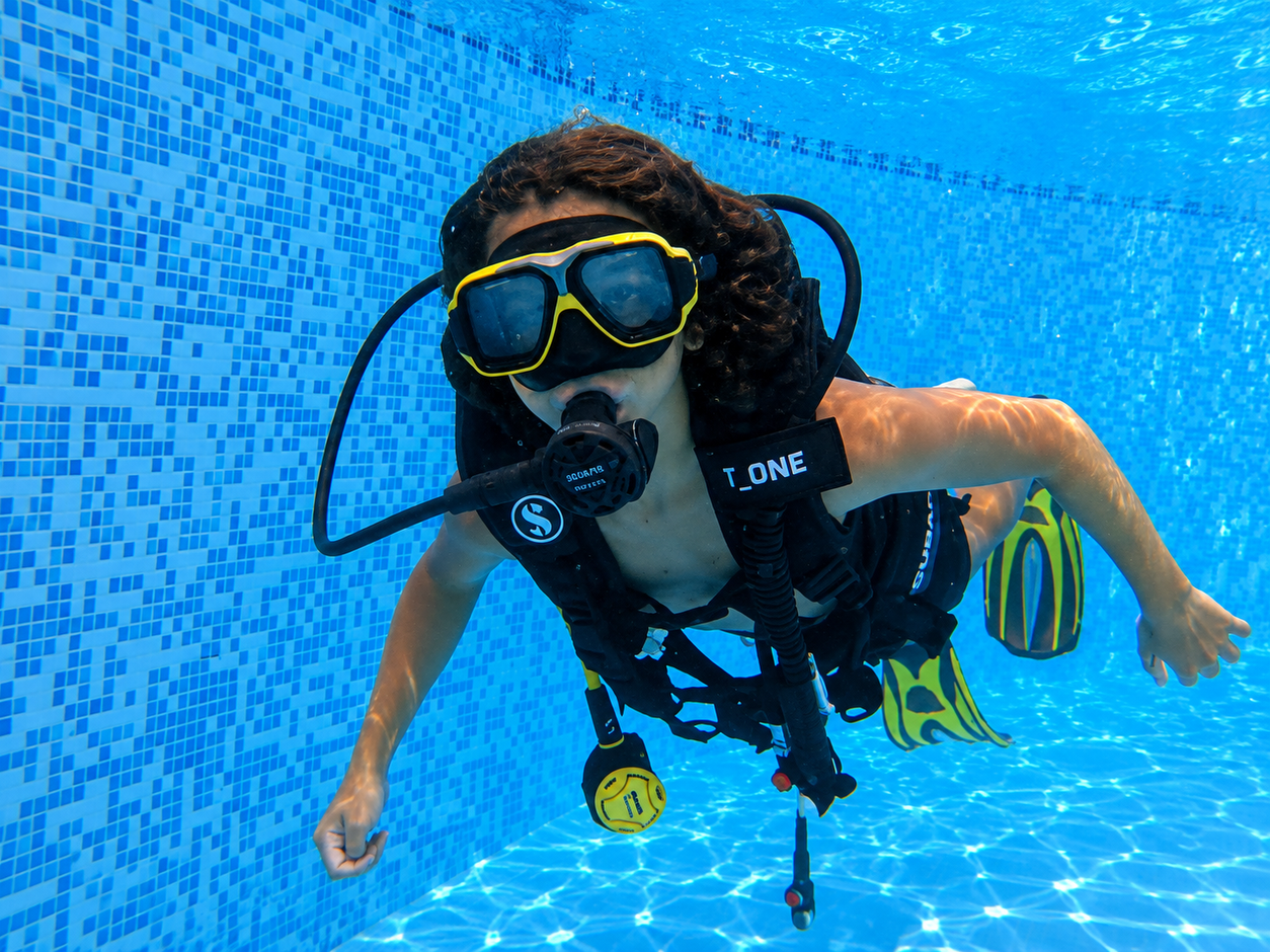 Young diver practicing underwater with scuba equipment in shallow water