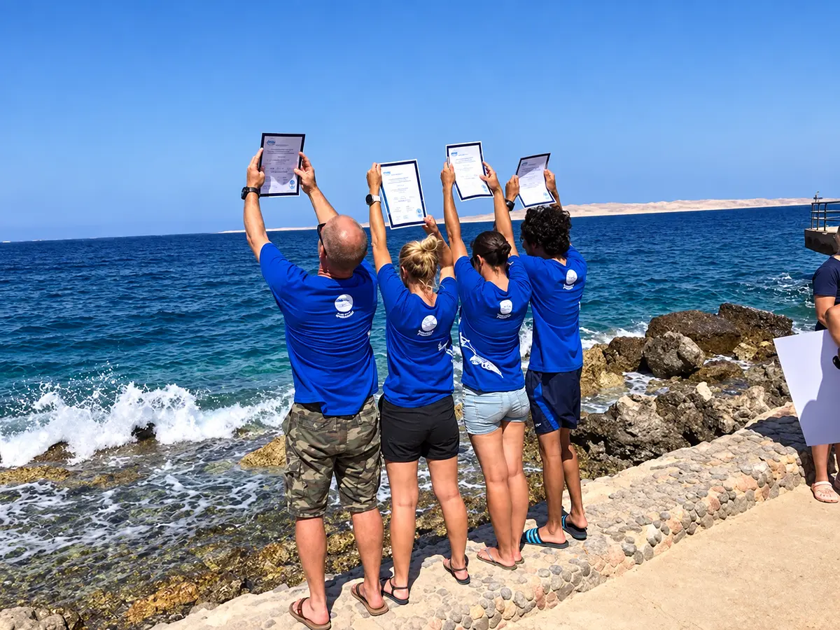 Course graduates holding certificates by the sea