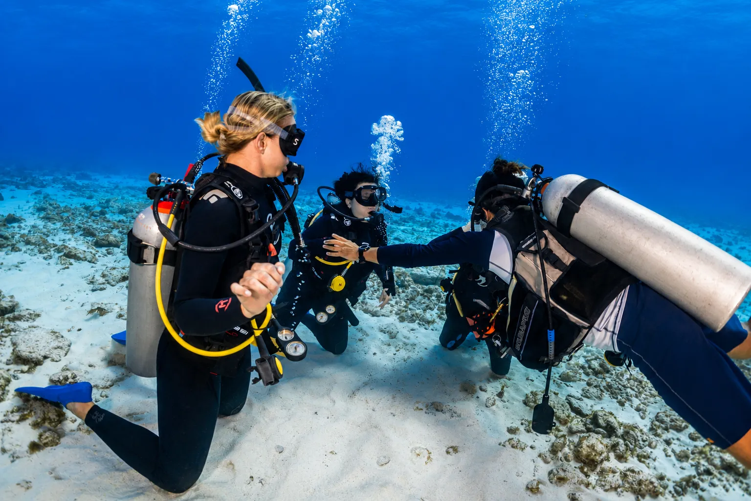 Scuba students kneeling on the sand during a training session